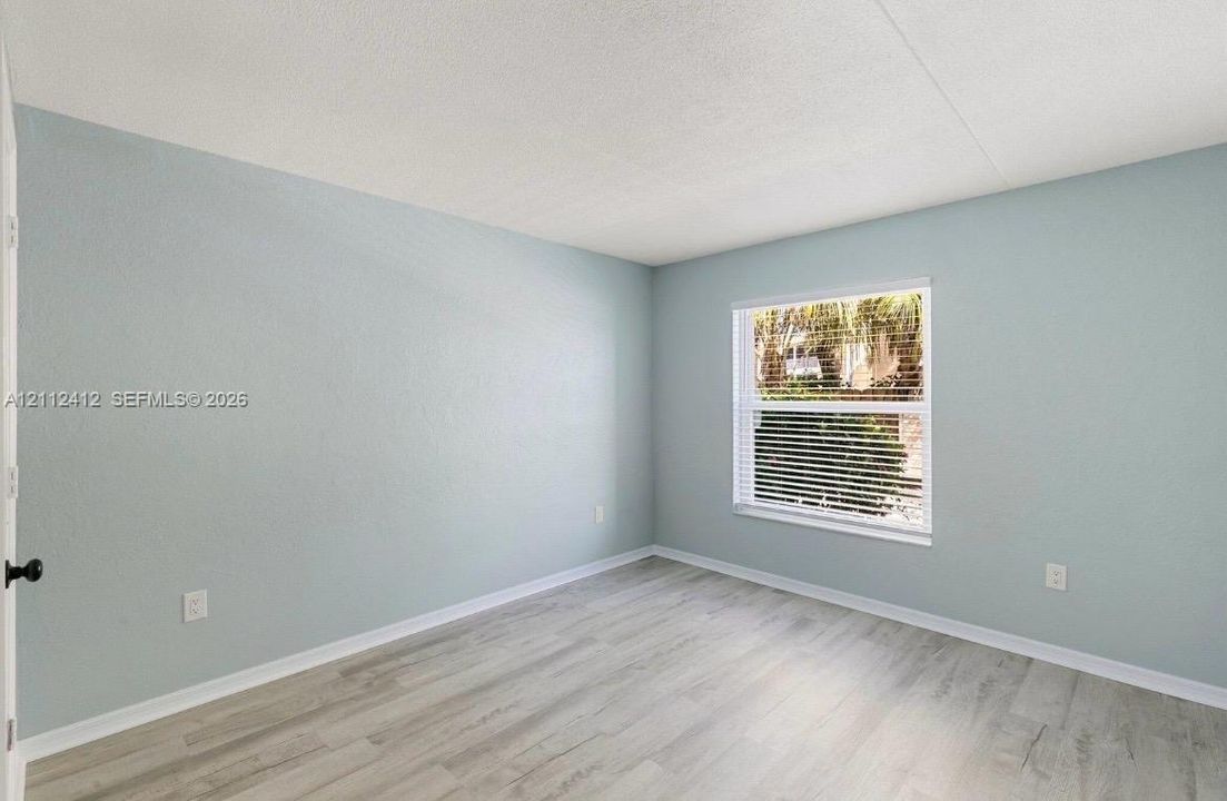 Neutral-toned wall paint, wood-finish flooring, and a single-pane window with adjustable horizontal blinds