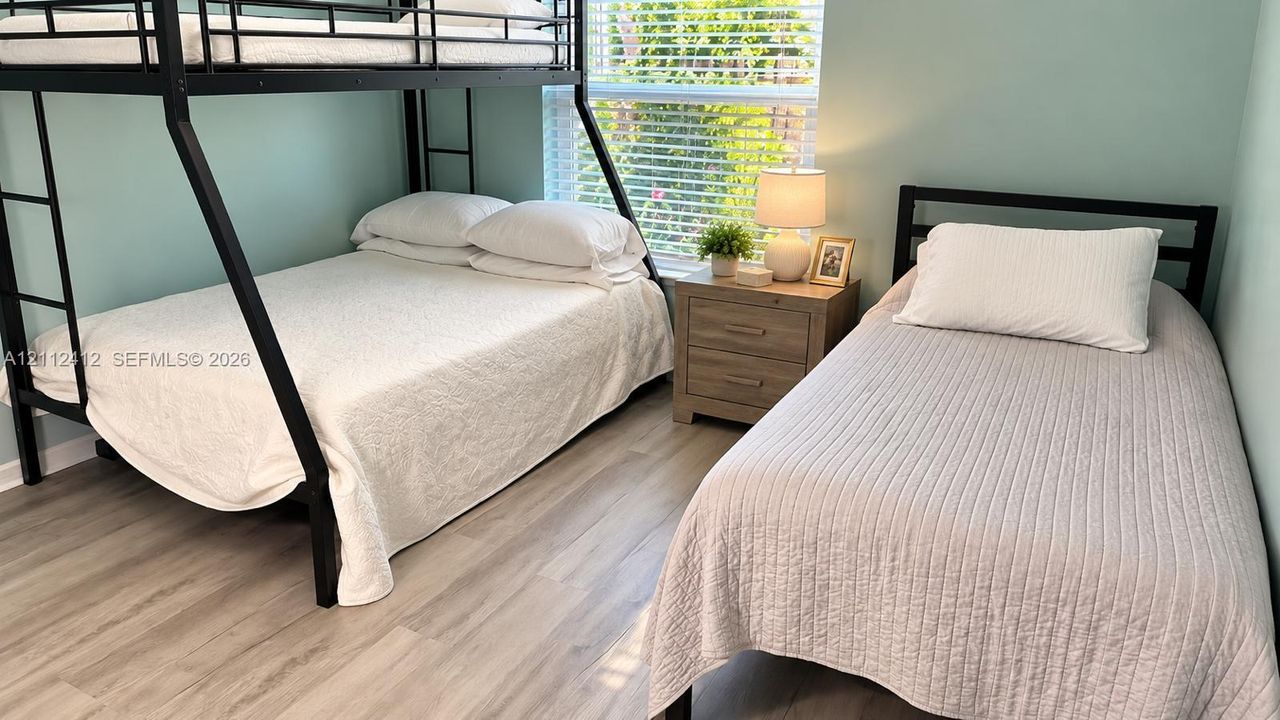 Bedroom featuring wood-finish flooring and a single-hung window with blinds