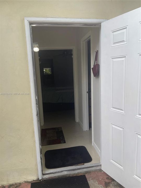 Six-panel white entry door with light-colored interior walls and neutral-tone flooring