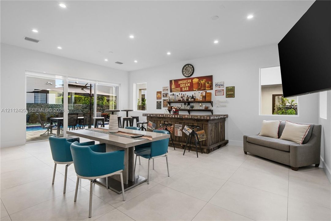 Open-concept space featuring large-format tile flooring, recessed lighting, a built-in wooden bar, and sliding glass doors