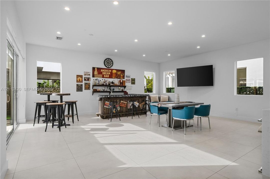 Spacious room featuring large-format tile flooring, recessed lighting, and a built-in bar area with wood cabinetry