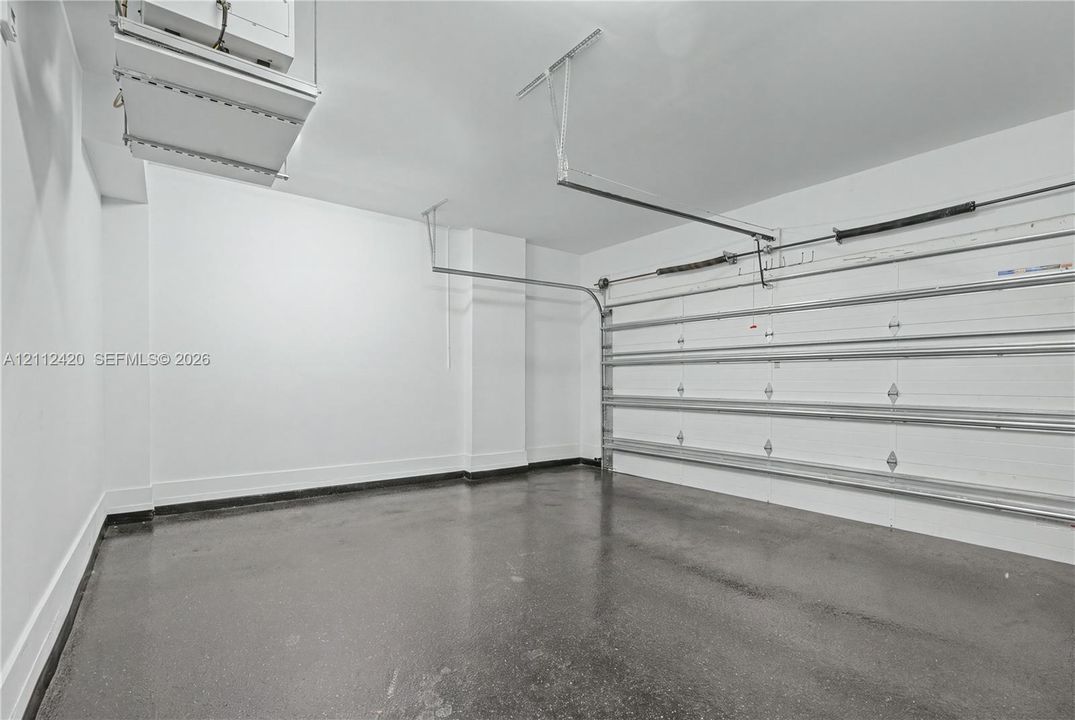 Attached garage featuring finished walls, smooth concrete flooring, and an automated overhead door system