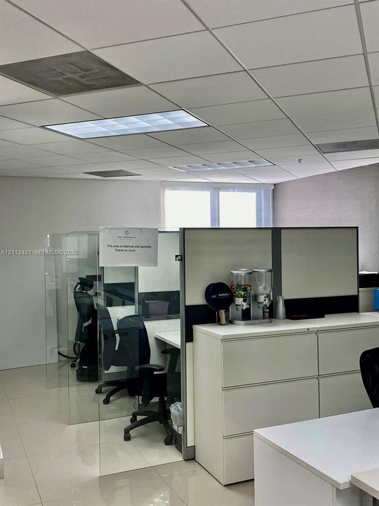 Drop ceiling with recessed lighting and neutral-toned floor tiling featuring integrated modular partitions with glass panels and built-in storage cabinetry