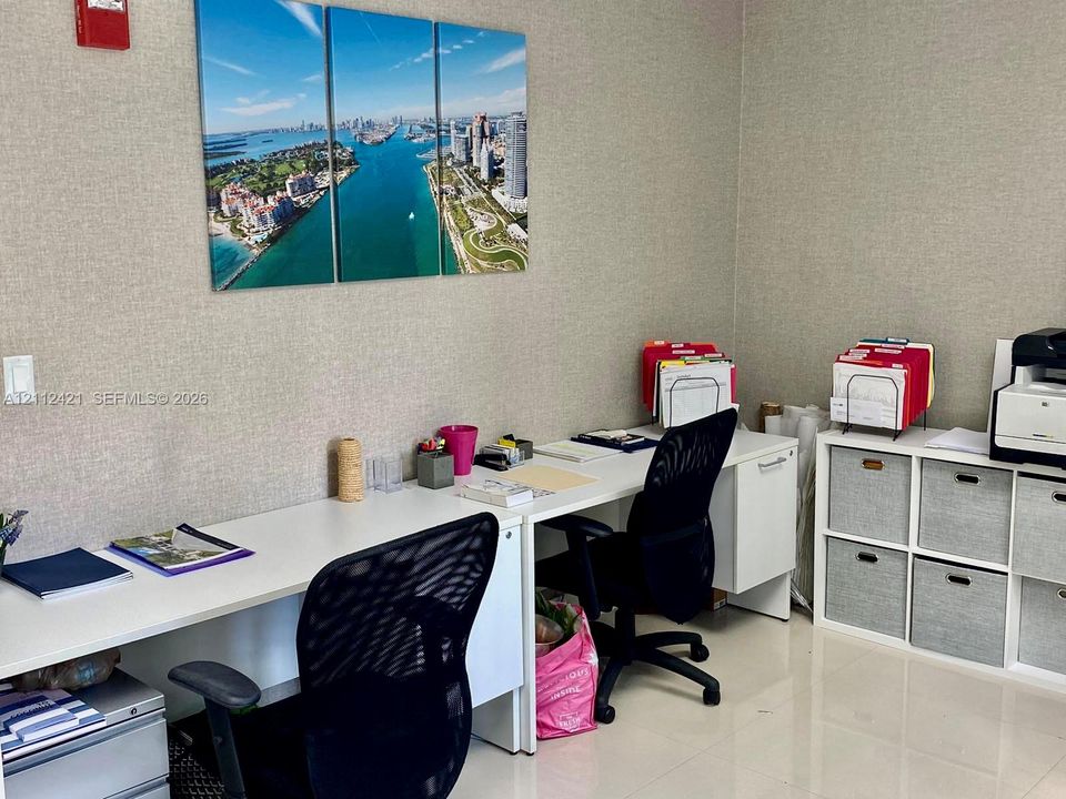 Built-in workspace featuring a dual-person desk with a solid white surface and neutral-toned wall covering