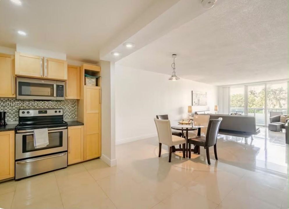 Kitchen featuring light-finish cabinetry, stainless steel appliances, and a decorative tile backsplash, paired with large-format tile flooring and recessed lighting