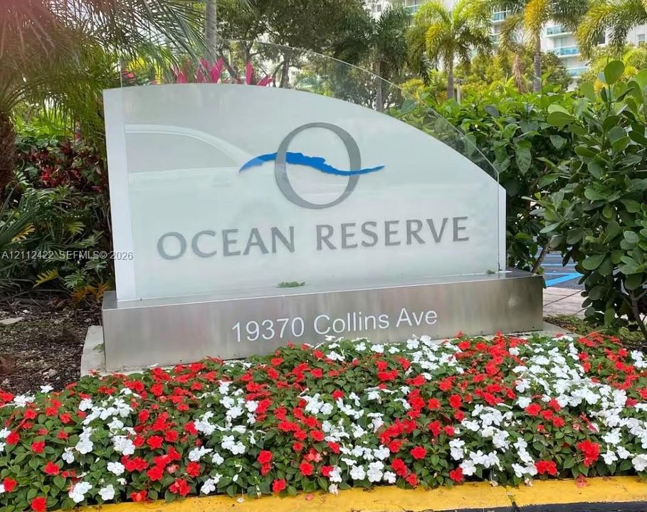 Ocean Reserve monument signage featuring a glass-panel display with brushed-metal base and surrounding manicured garden beds