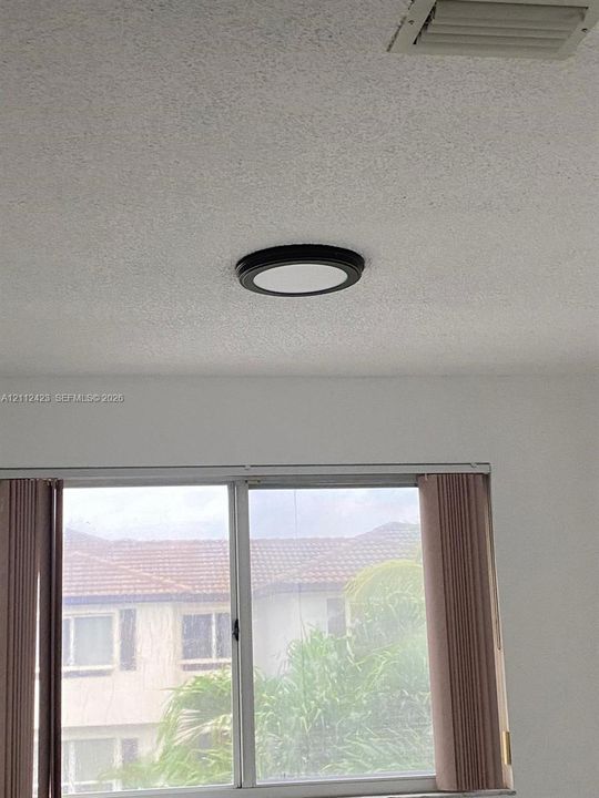Flush-mount circular ceiling light fixture with a matte black frame and textured ceiling finish