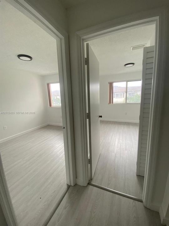 Rooms featuring wood-finish flooring, sliding windows, and flush-mount lighting fixtures, including a room with bi-fold closet doors