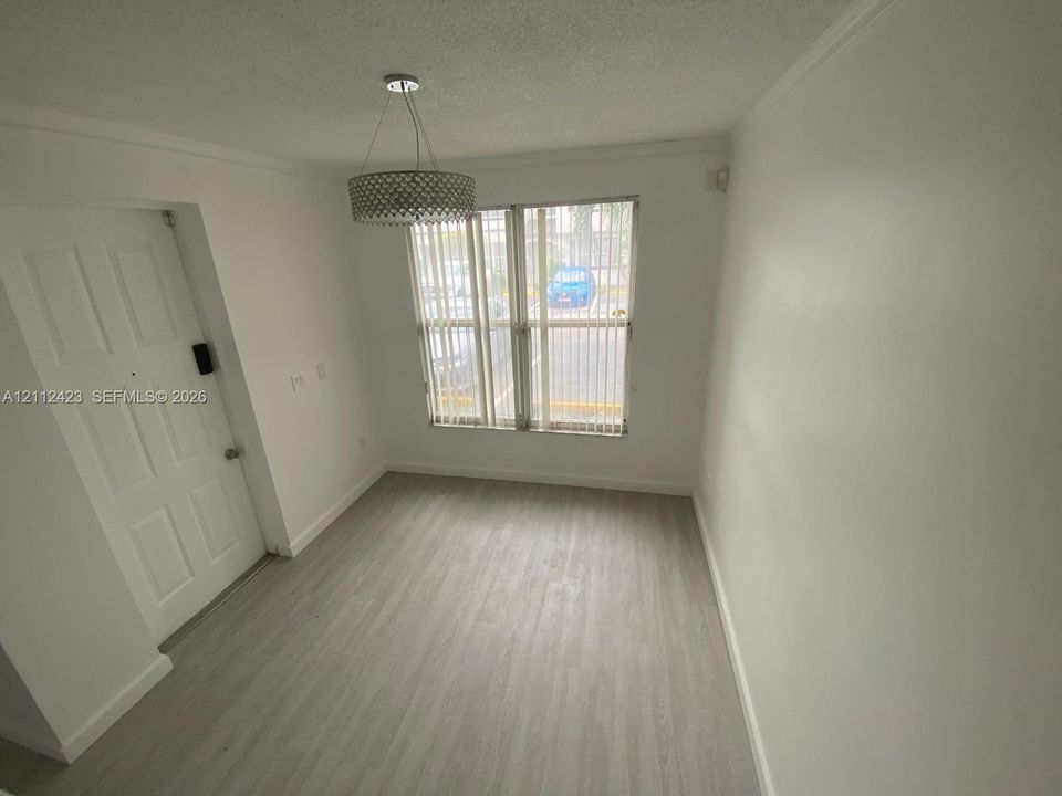 Interior space featuring wood-finish flooring, a multi-panel door, double-window configuration with vertical blinds, and a circular drum pendant light fixture