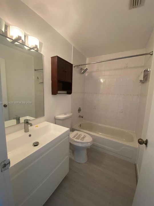 Modern vanity with a rectangular sink, chrome-finish faucet, full-width mirror, wall-mounted storage cabinet, and wood-finish flooring
