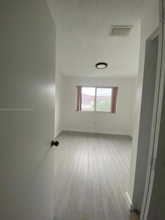 Interior room featuring neutral wall finishes, wood-finish flooring, a flush-mount circular light fixture, and a dual-pane sliding window