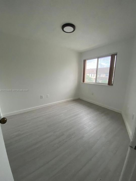 Neutral interior featuring wood-finish flooring, a flush-mount circular ceiling fixture, and a sliding window
