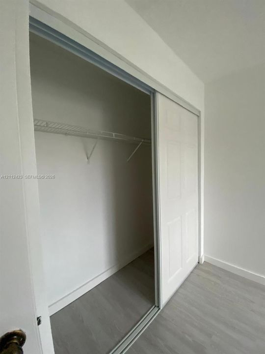 Closet featuring white sliding doors and integrated wire shelving over wood-finish flooring
