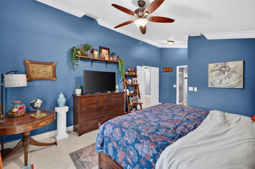 Vaulted ceilings with crown molding, ceiling fan with light kit, and tile flooring