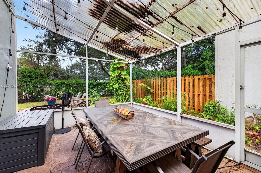 Screened-in patio featuring a textured tile floor, corrugated overhead covering, and screen enclosure