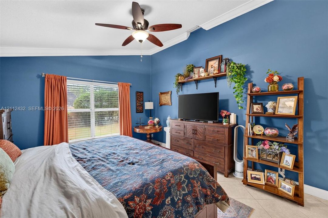 Vaulted ceilings, crown molding, multi-blade ceiling fan with integrated lighting, and tile flooring