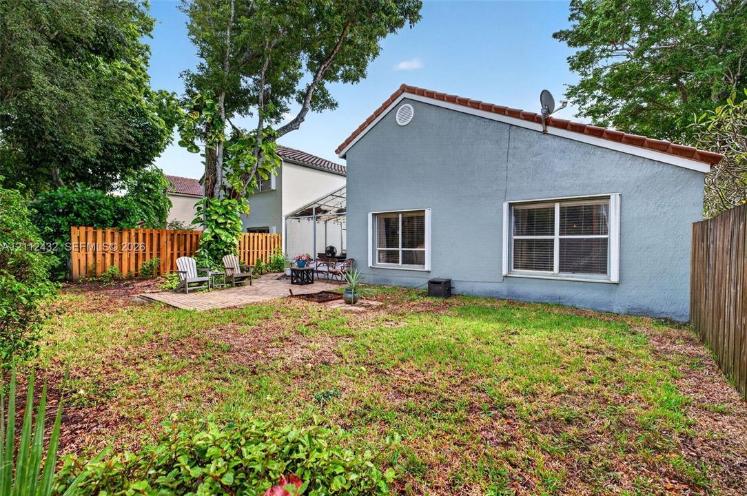 Rear exterior featuring stucco siding, tile roof, brick paver patio