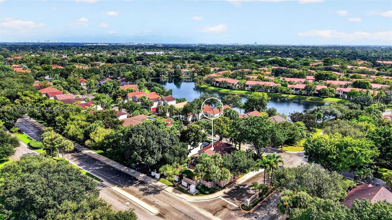 Aerial perspective of property featuring a tile roof, mature landscaping, and proximity to a neighborhood lake