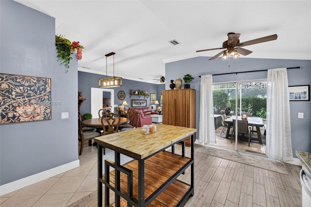 Open kitchen area featuring vaulted ceilings, wood-look tile flooring, sliding glass doors, and a multi-light metal chandelier