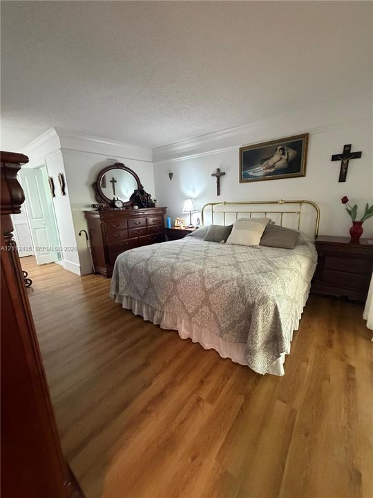 Bedroom featuring wood-finish flooring, crown molding, and multi-panel interior doors