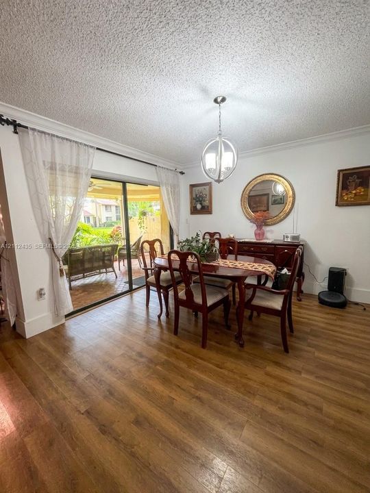 Wood-finish flooring, sliding glass door, spherical metal pendant lighting, and crown molding
