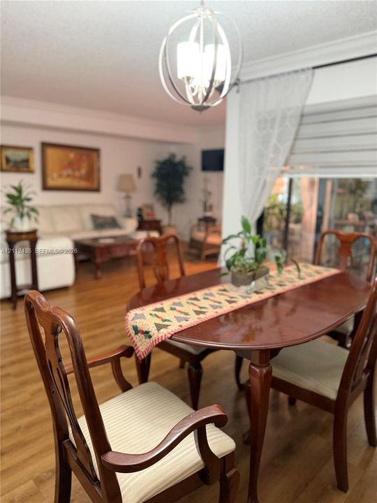Open floor plan featuring wood-finish flooring, crown molding, and a spherical metal chandelier with multi-light fixture