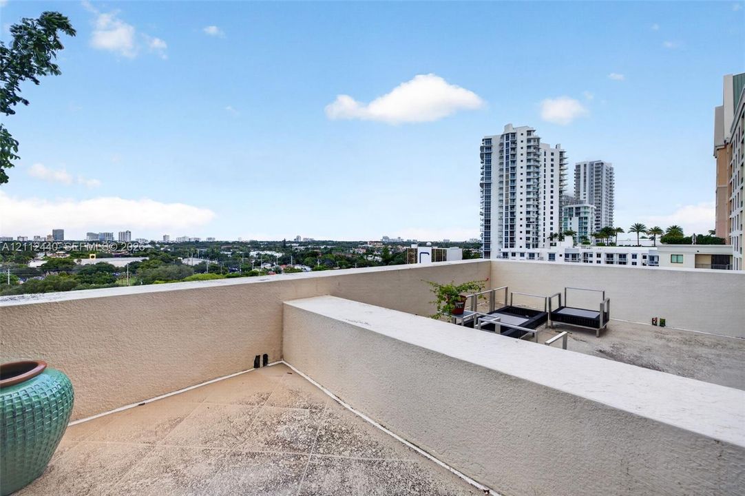 Open-air rooftop terrace featuring concrete tile flooring and a stucco parapet wall
