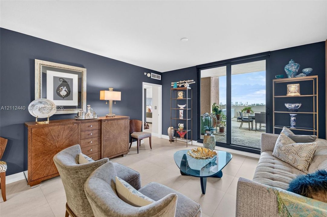 Living area featuring large-format porcelain flooring, floor-to-ceiling impact glass sliding doors, and a private OVERSIZED balcony