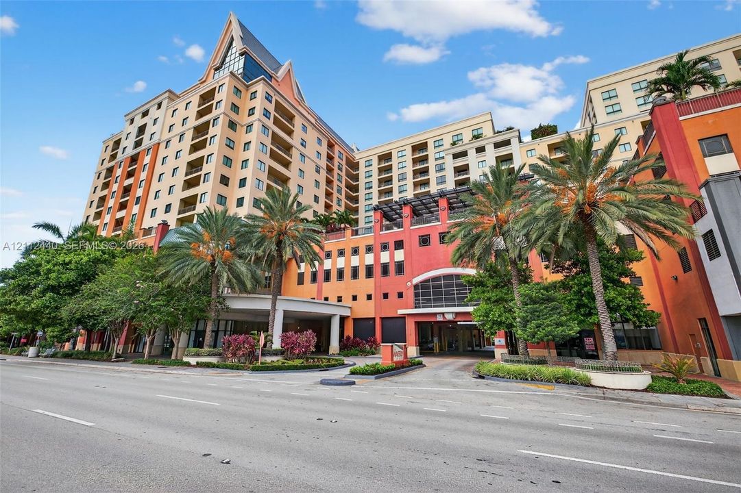 High-rise building featuring private balconies, a porte-cochère entryway, and mature palm tree landscaping