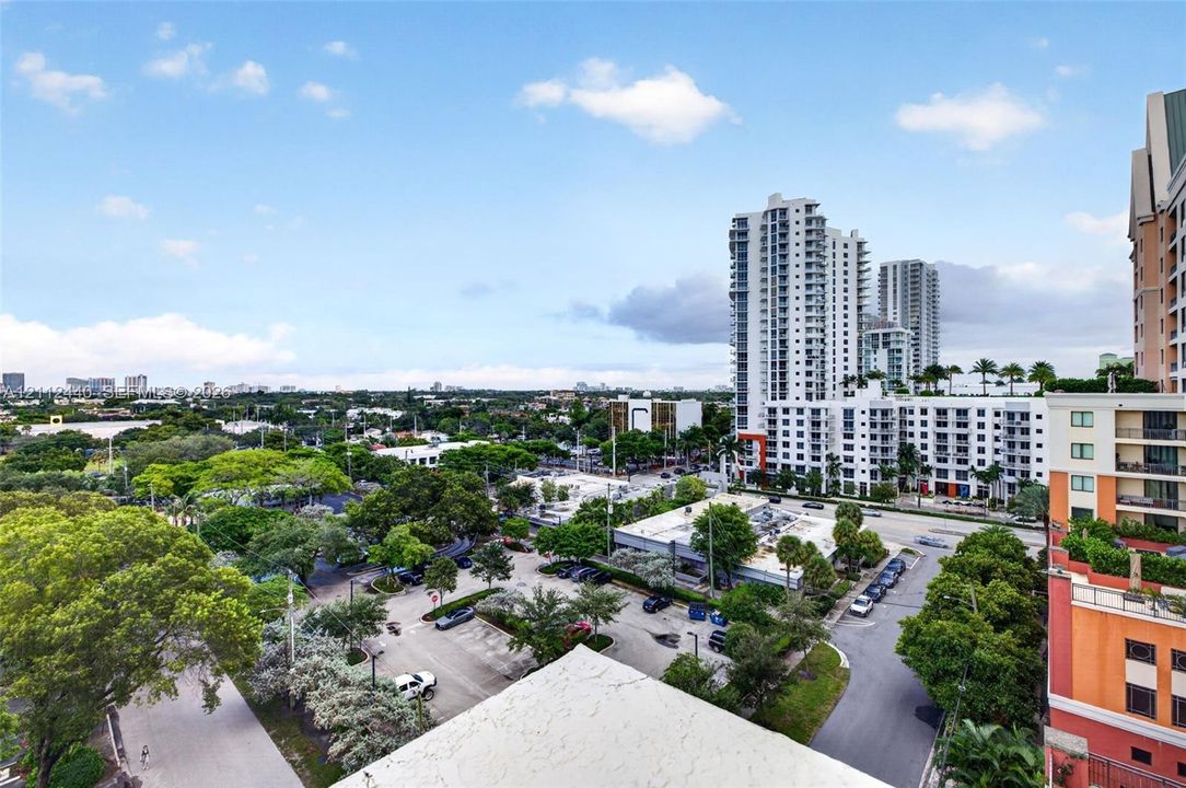 Elevated panoramic perspective featuring urban architecture, multi-story high-rise buildings, and mature canopy trees