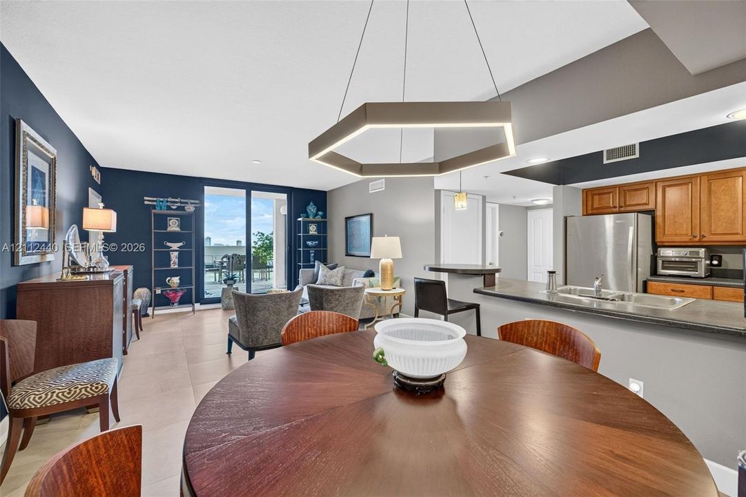 Open-concept area featuring porcelain flooring, kitchen breakfast bar - upgraded wooden cabinetry, and sliding glass doors to the huge terrace (chandelier does not convey)