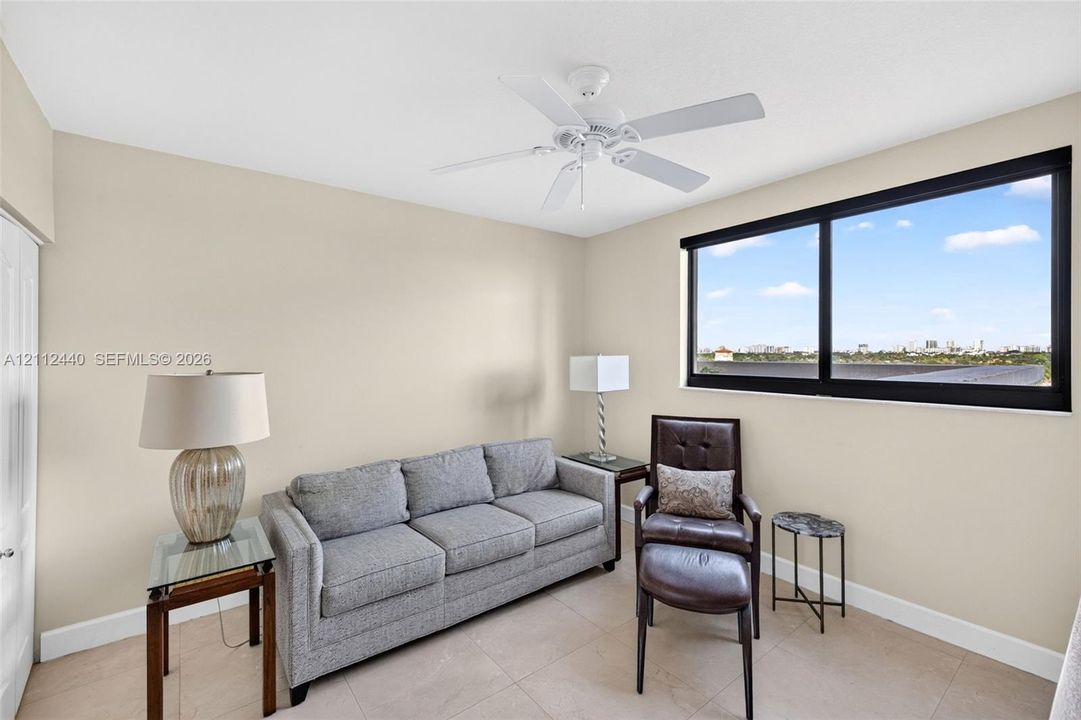 Neutral interior walls, large black-framed picture window, tile flooring, and white ceiling fan with light fixture