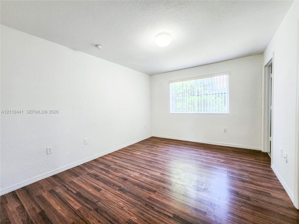 Interior space featuring wood-finish flooring, white walls, and a recessed ceiling light fixture