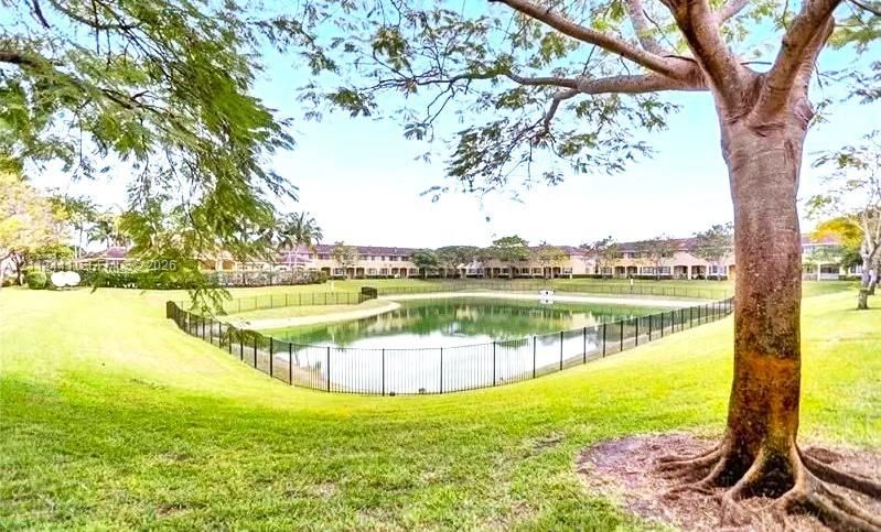 Expansive grounds featuring a pond, metal perimeter fencing, and mature trees