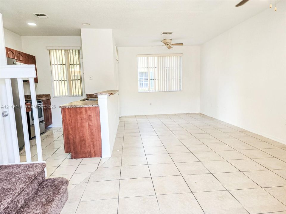 Open-concept floor plan featuring ceramic tile flooring, kitchen breakfast bar, wooden cabinetry, and dual ceiling fans