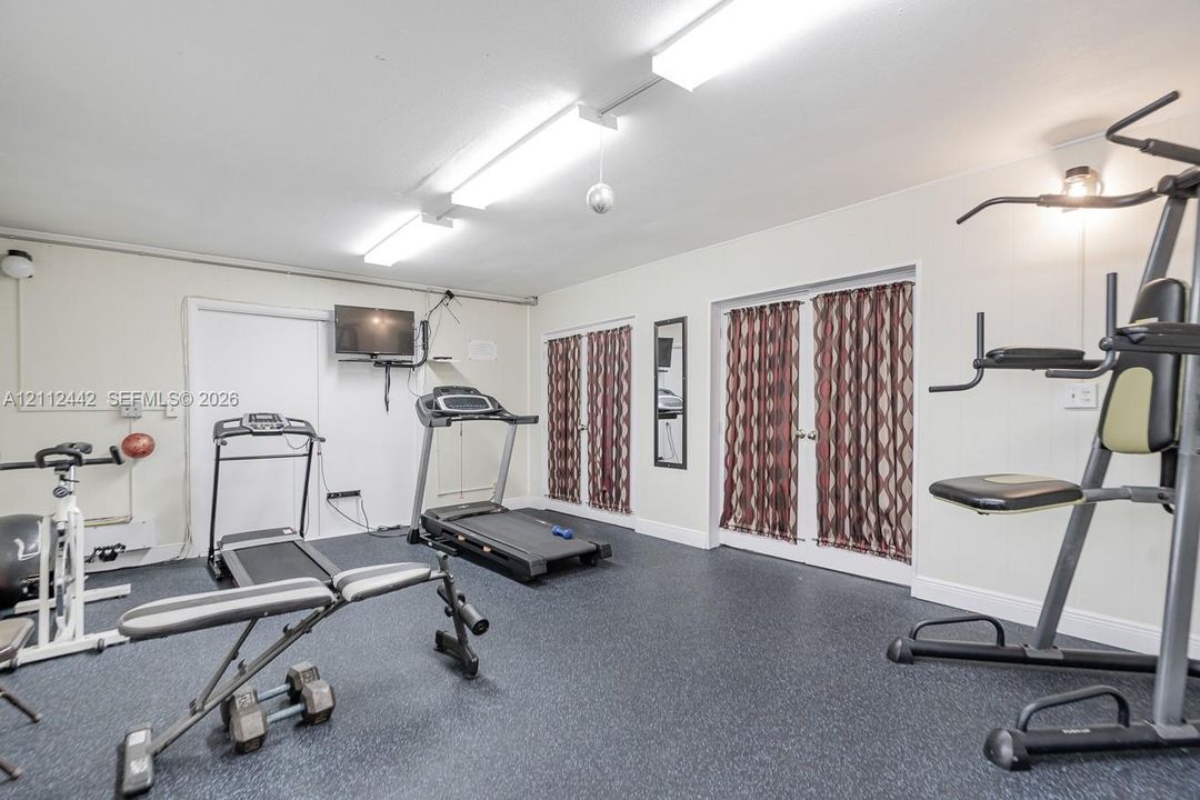 Interior room featuring dark rubber flooring, white walls, and dual sets of glass-paneled doors with metallic hardware