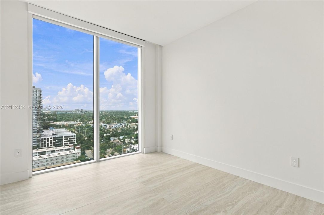 Floor-to-ceiling windows, neutral interior walls, and stone-finish flooring