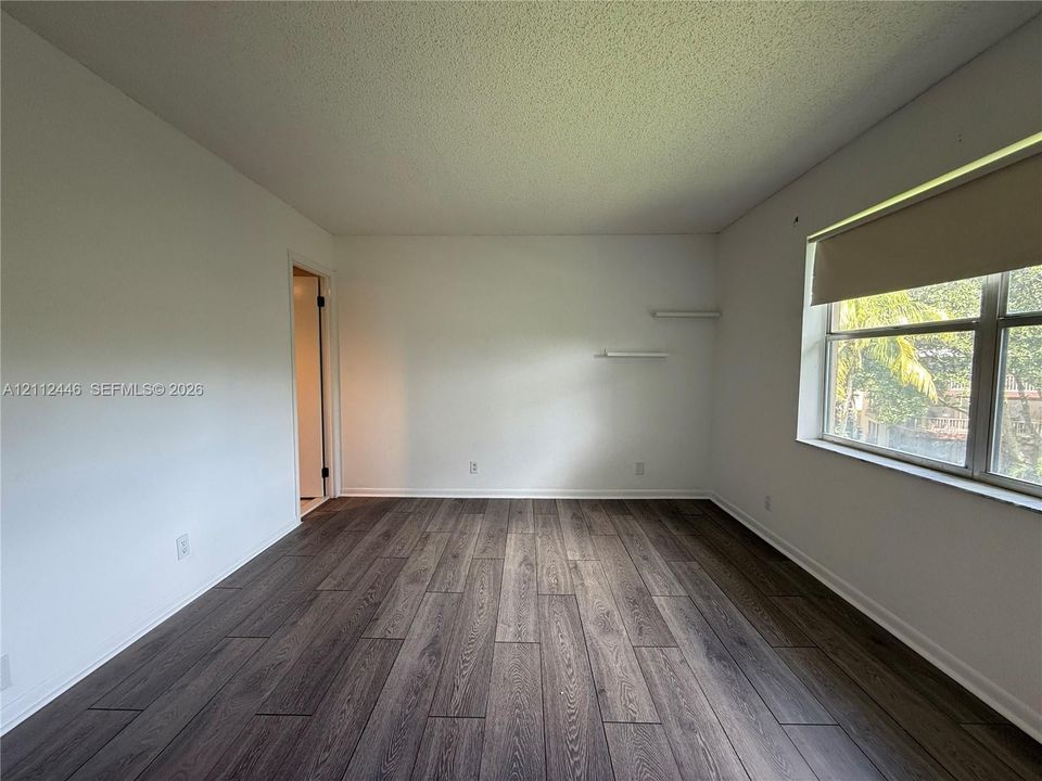Room featuring wood-finish flooring, white walls, and built-in wall shelving