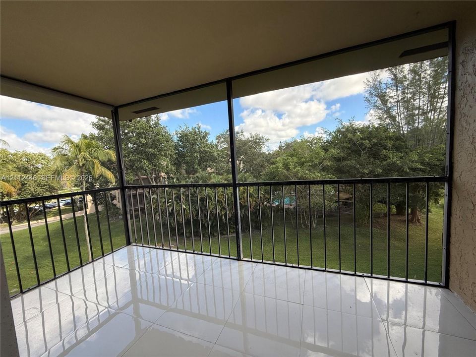 Screened-in balcony featuring white tile flooring, black metal railing, and a textured stucco ceiling