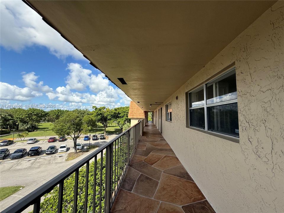 Exterior walkway featuring flagstone-style flooring, a metal railing, and stucco wall finishes