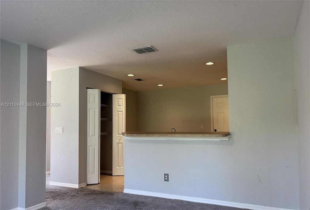 Pass-through breakfast bar with stone-surfaced countertop, recessed ceiling lighting, and built-in closet with shelving