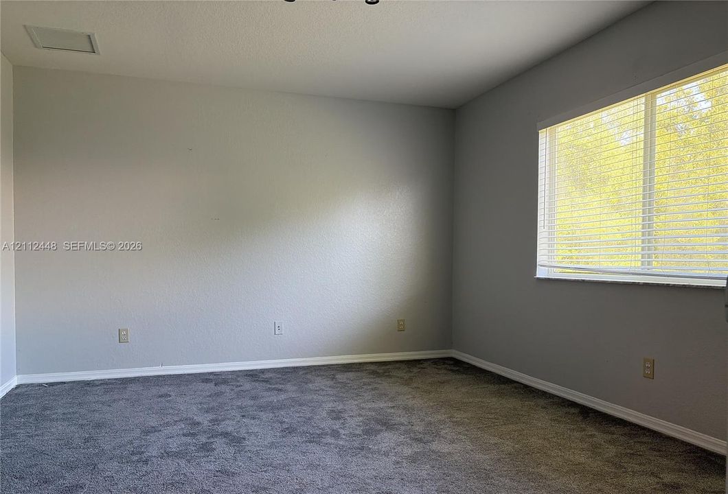 Neutral wall paint, carpeting, and horizontal window blinds