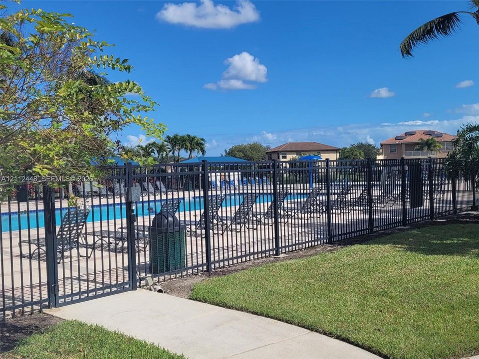 Outdoor swimming pool featuring a concrete deck and black metal perimeter fencing