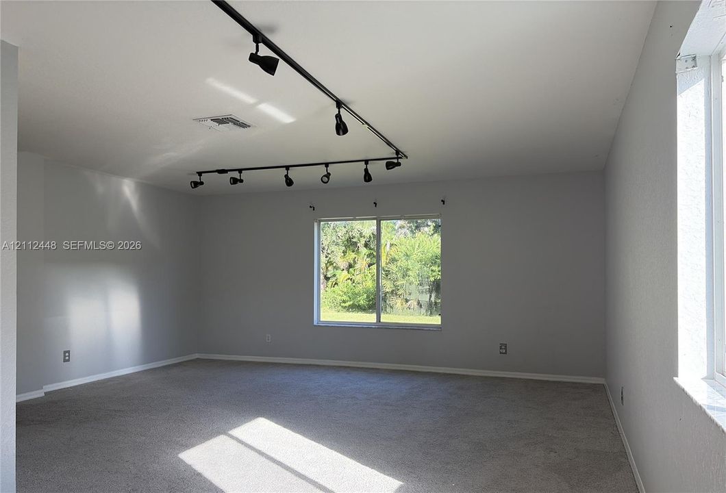 Interior space featuring wall-to-wall carpeting, neutral-toned walls, and black industrial-style track lighting