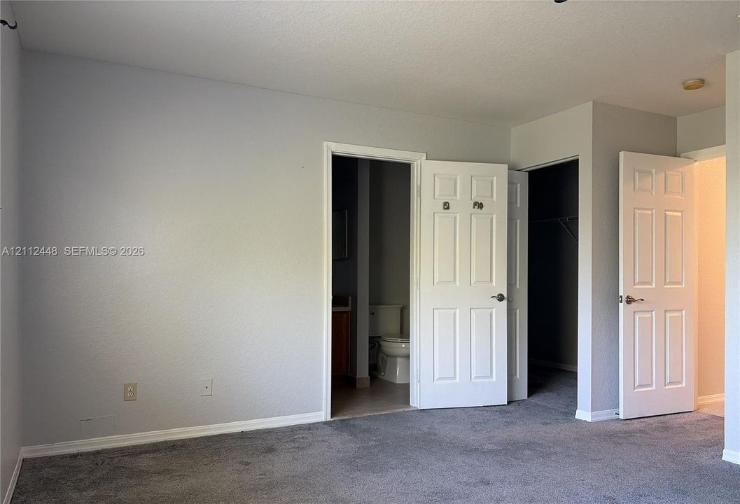 Neutral grey wall paint, wall-to-wall carpet, and multiple six-panel interior doors