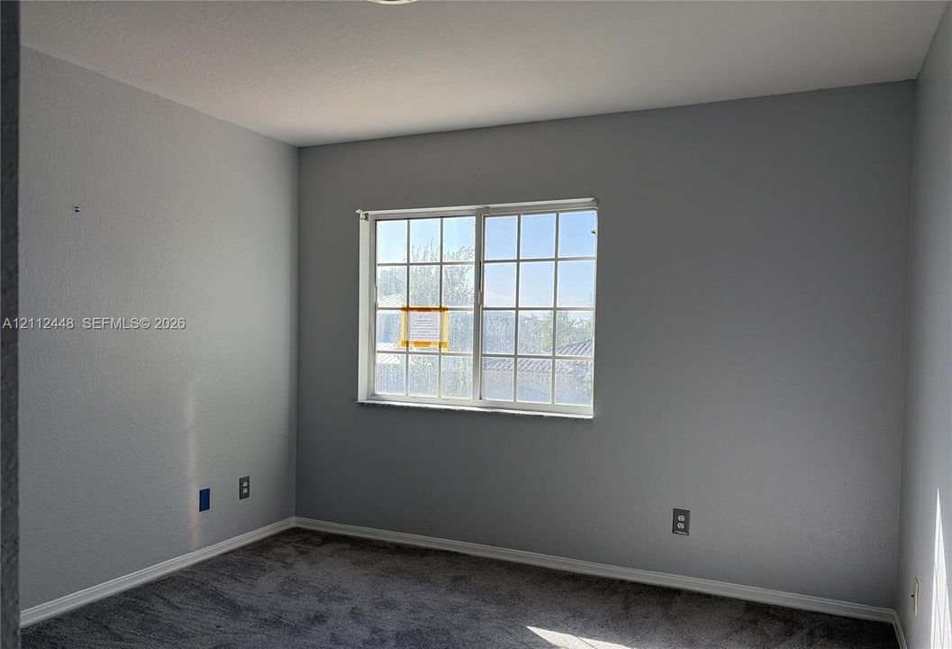 Neutral-toned walls, gray carpeting, and a multi-pane sliding window