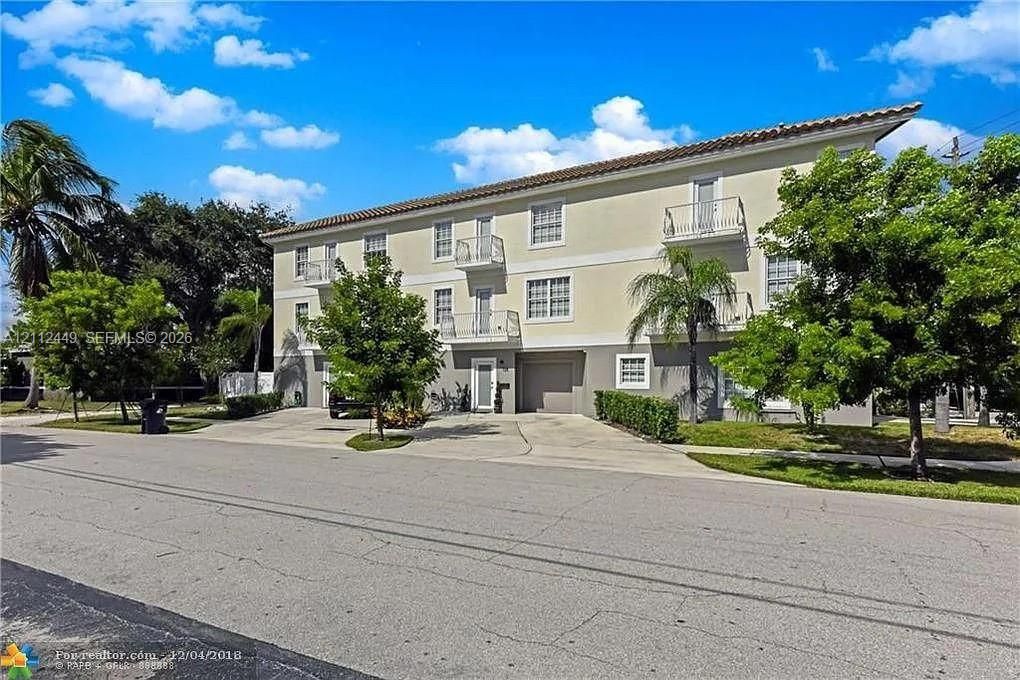 Multi-level exterior featuring a tile roof, stucco facade and private balconies.