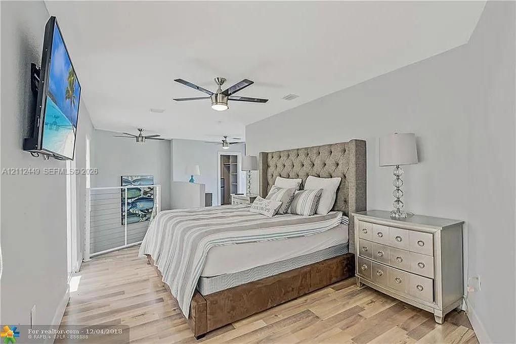 Wood-finish flooring, multi-blade ceiling fans, and an industrial-style metal railing