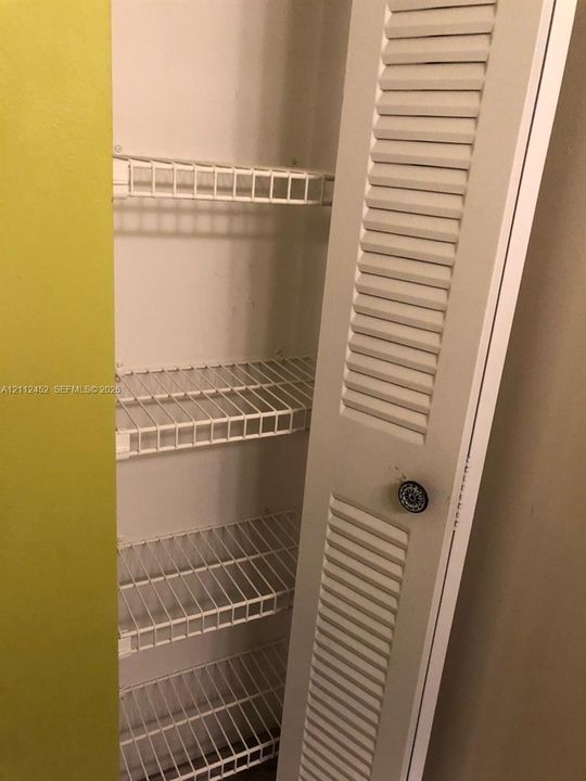 Storage closet featuring louvered bi-fold doors and multiple built-in wire shelving units