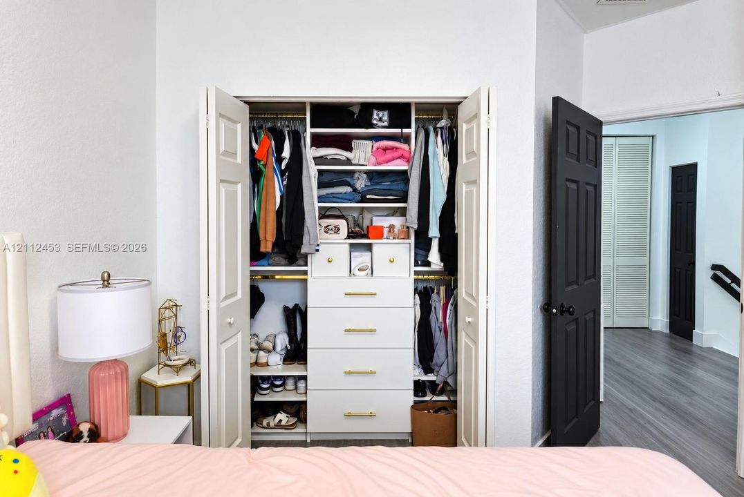 Closet featuring bi-fold doors, built-in shelving, integrated drawers with brass-finish hardware, and dual hanging rods